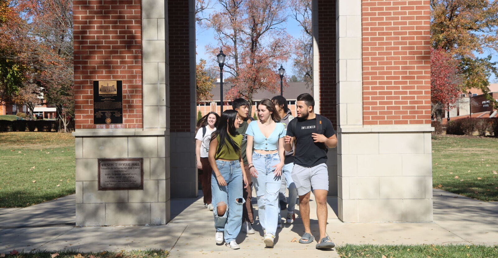 Group of students walking under brick archway